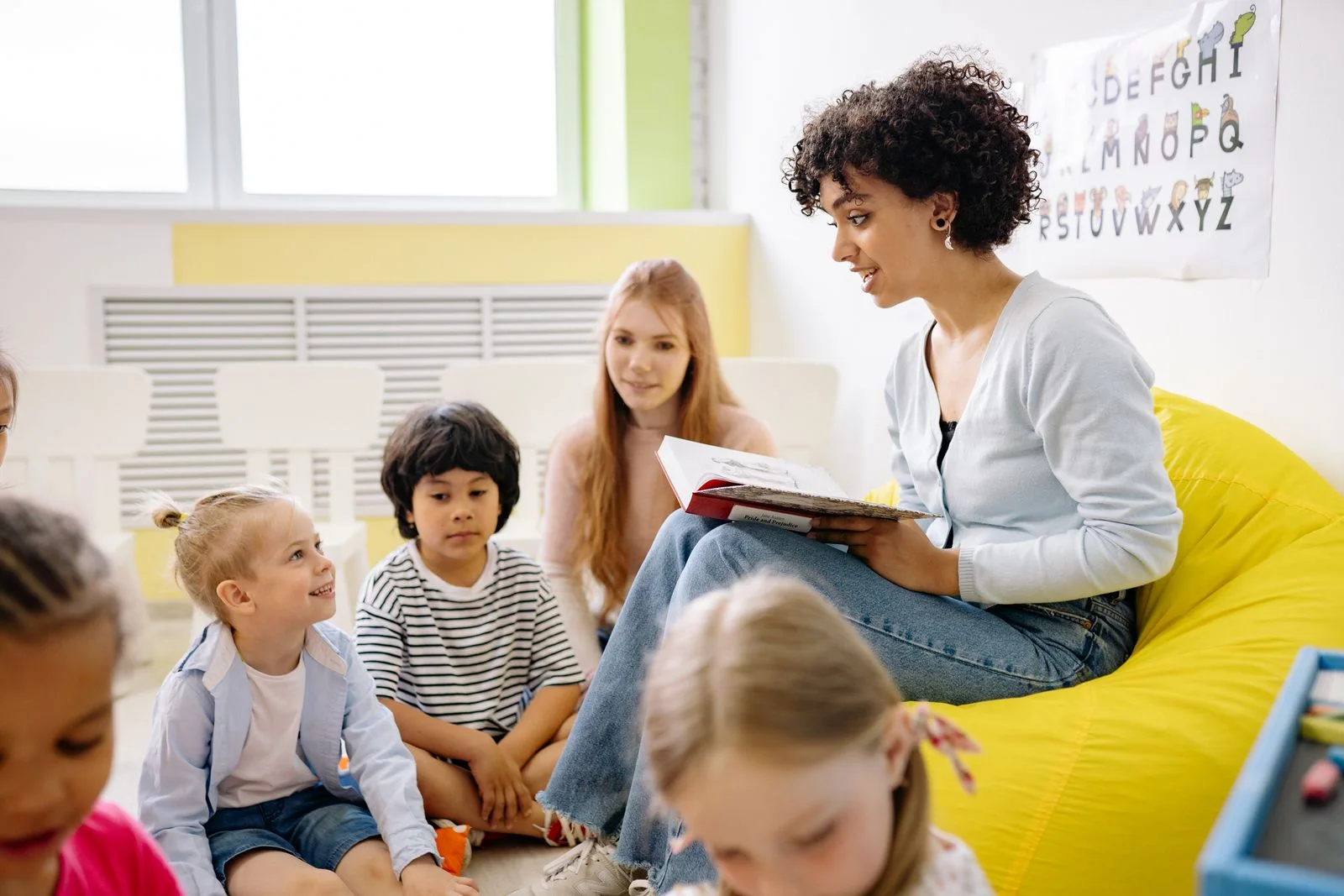 Teacher reading with a diverse group of children in a bright classroom