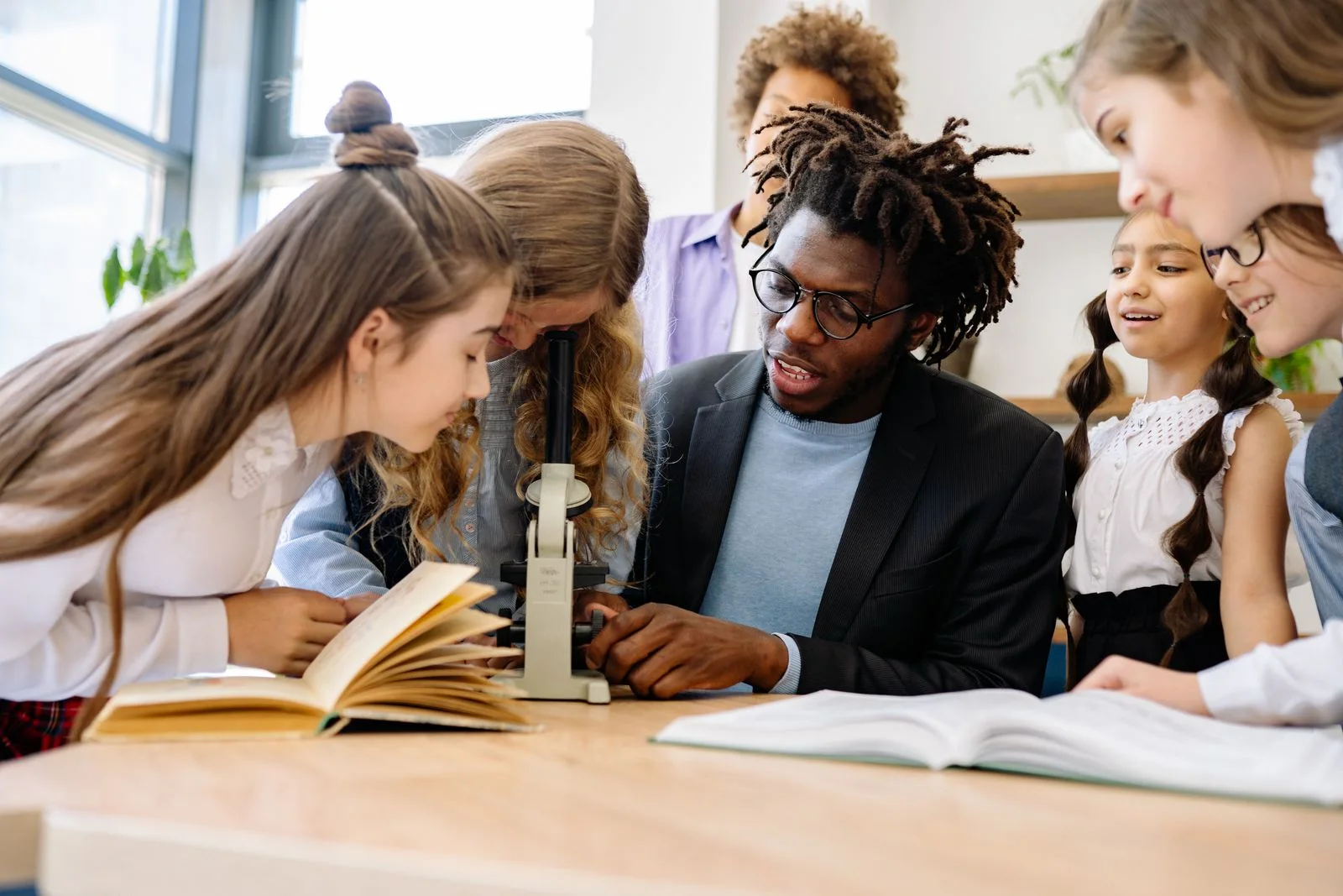 Teacher guiding a diverse group of students through a classroom science activity